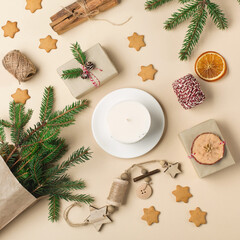 Festive Xmas decorations, homemade gingerbread cookies, fir branches on natural beige background.