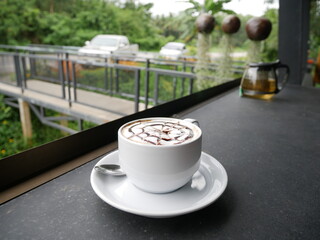 Coffee latte in a white cup on a stone counter in a coffee shop.