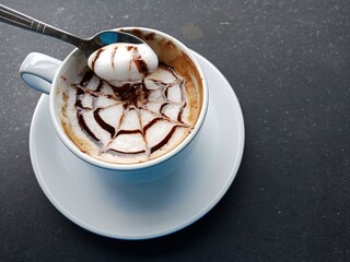 Coffee latte art in a white cup placed on a gray stone surface.