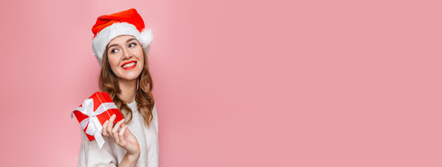 Christmas banner with girl in santa hat and gift box isolated on pink background