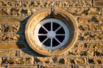 Fototapeta na wymiar A wagon wheel functioning as a window embedded in a sandstone wall