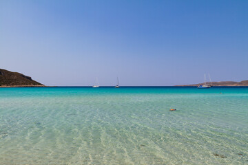Fototapeta premium Simos bay at Elafonissos, south Greece. A peacefull scenery with turquoise water and blue sky. A few sailing boats in the horizon. Wide angle photo with clear depth of view