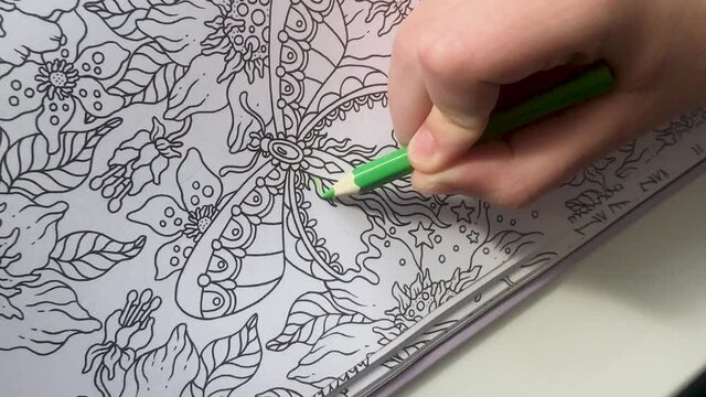 Someone's young hand paints anti-stress coloring patterns with a green pencil. zen art, doodle patterns in black and white. Zen Doodle, zen tangle illustration, coloring books for adult and kids