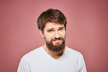 Obraz premium Emotional bearded man in white T-shirt discontent pink background