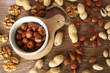 various nuts are scattered on a wooden background. nuts in a white plate. close-up