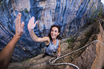 Emotional girl gives five to a friend, A woman is climbing in Turkey, Overcoming the fear of heights. - obrazy, fototapety, plakaty