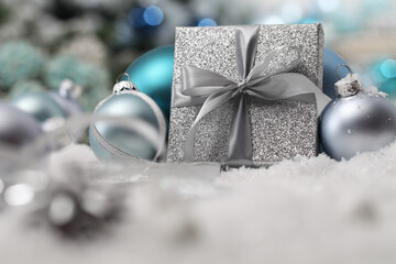 Merry christmas background, silver gift present package with bow and ribbon, next to blue christmas balls and snowflakes, useful as a greeting card template with copy space 