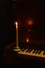 Burning candle on old piano for cozy