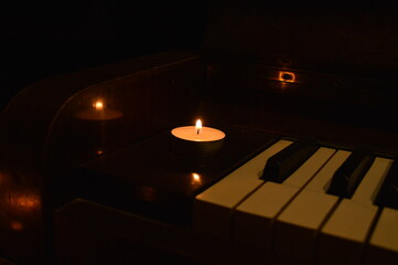 Burning candle on old piano for cozy