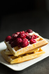 Belgian waffles with raspberries on dark background