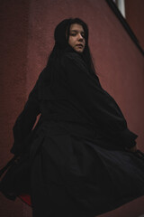 A girl in a black cloak on a red background.
