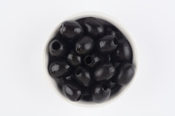 Aceitunas negras sin hueso en un bol de cerámica blanco, vista desde arriba