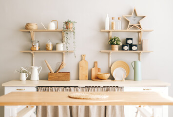 Bright kitchen in the Provence style with houseplants, wooden dishes and kitchen accessories on the table and shelves.