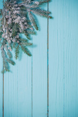fir branches in snow on blue wooden background