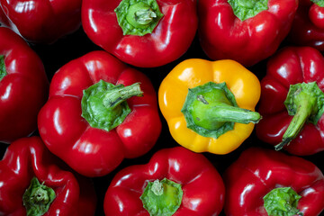 Red peppers and one yellow pepper on a dark background