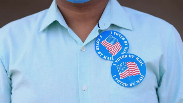 Voting Fraud Concept. Lack of trustworthiness for Mail-in voting. Man puts multiple I Voted By Mail stickers on the shirt.