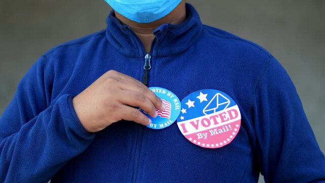 Voting Fraud Concept. Lack of trustworthiness for Mail-in voting. Man puts multiple I Voted By Mail stickers on the shirt rack focus