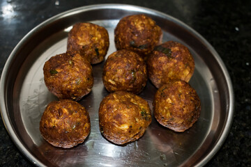  Indian Vegetarian koftas made with bottle gourd and gram flour as a main ingredients with onion, coriander leaf kept aside after deep frying.
- 387813416
