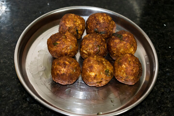  Indian Vegetarian koftas made with bottle gourd and gram flour as a main ingredients with onion, coriander leaf kept aside after deep frying.
- 387813486