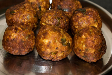  Indian Vegetarian koftas made with bottle gourd and gram flour as a main ingredients with onion, coriander leaf kept aside after deep frying.
- 387813647