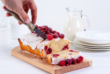 Yogurt gluten free pound cake with raspberries and sugar glaze on a white background