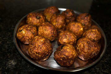  Indian Vegetarian koftas made with bottle gourd and gram flour as a main ingredients with onion, coriander leaf kept aside after deep frying.
- 387813859