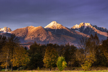 Sunset Over Tatra Mountains Ridge. Snow Caped Peaks and Beautiful Autumn Colors of Trees Foliage