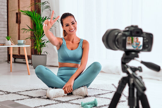 Young beautiful sporty woman vlogger is making video training for blog exercising in front of a home camera.