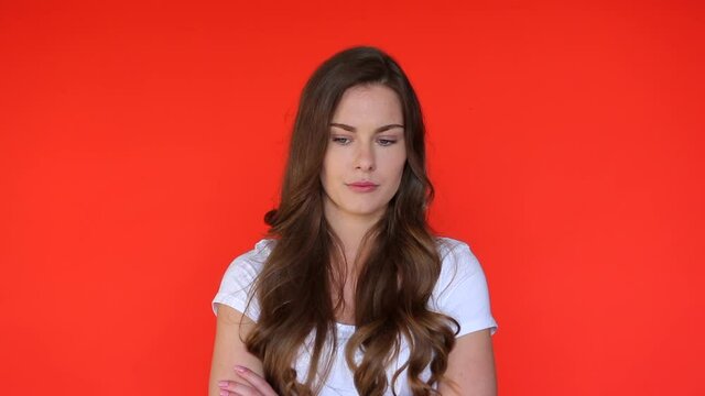 Arrogant woman bored face. Moody woman upset in red studio. Angry girl standing with crossed arms isolated. Female contempt attitude. Annoyed person grumpy emotion. Unhappy woman expression