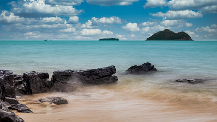 view of clam wave on the rock on the beach with blue sky and white cloud.