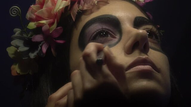 Latin woman painting her face with a mexican skull make up art