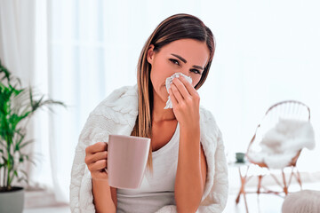 Sick woman with headache sitting under the blanket. Sick woman with seasonal infections, flu, allergy sitting on the bed.