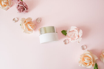 Natural cosmetics products series advertising composition on pink pastel  background with roses  flowers  . Moisturizing face cream jar and floral decoration . Top view, flat lay, copy space.Beauty 