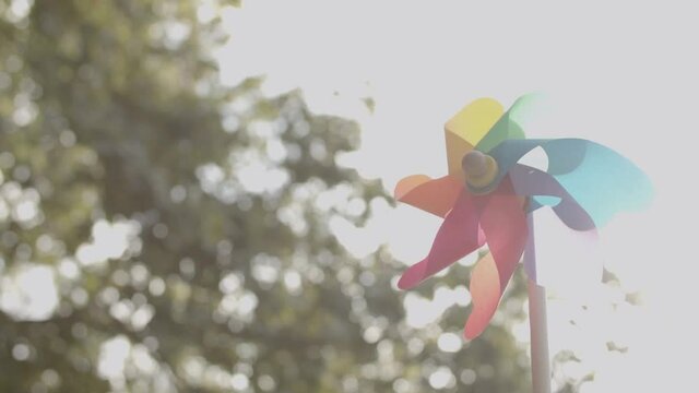 Colorful paper fun on wooden stick swirling on blurred background. Bright toy for children and playing game on open air. Static camera. Childhood, weekend and summer activity concept