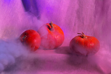 Three small pumpkin on a blue-purple linen background with fog. Halloween Abstract Party.