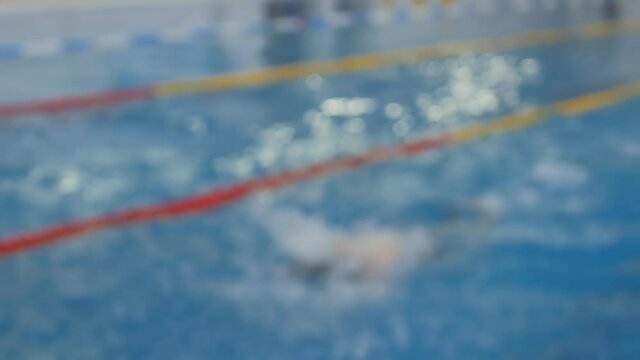 a sports judge holds a stopwatch in his hand and presses Finish when the swimmer touches the pool. But other swimmers are still swimming. Kids sports - Powered by Adobe