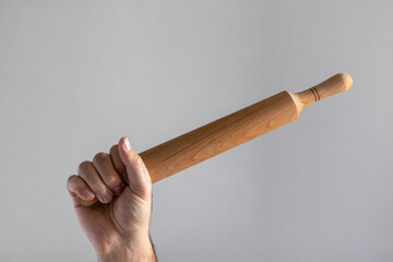 Rolling pin in male hand on gray background.