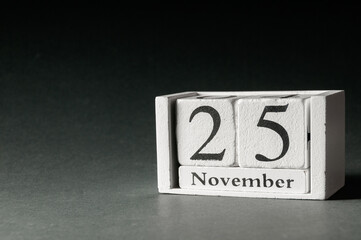 Wooden calendar on dark background, date25 November