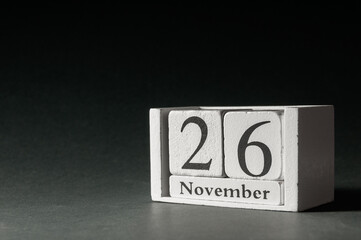 Wooden calendar on dark background, date 26 November