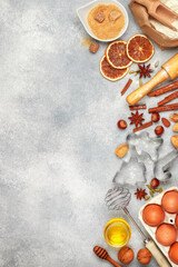 Christmas baking background with ingredients (flour, eggs, sugar, honey, nuts, spices, citrus candied fruits) for making homemade gingerbread cookies on a light concrete background. copy space