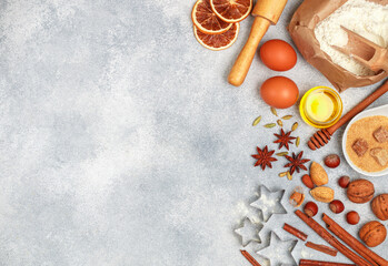 Fototapeta na wymiar Christmas baking background with ingredients (flour, eggs, sugar, honey, nuts, spices, citrus candied fruits) for making homemade gingerbread cookies on a light concrete background. copy space