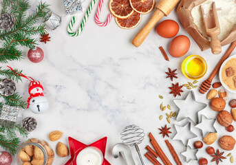Christmas baking background with ingredients for making homemade gingerbread cookies on a marble background. Spruce branches, toys and spices (cinnamon, cardamom, star anise) on the table. copy space