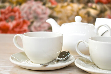 White cup and teapot on the background of a cozy interior in the restaurant. A couple of tea on the table. Space for text