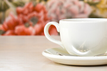 White cup with tea or coffee on the background of a cozy interior in a restaurant. Fresh drink on a table in a cafe, breakfast. Place for text and design