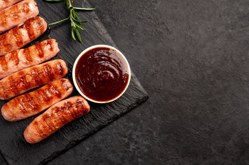 classic grilled sausages and sauce on a stone background with copy space