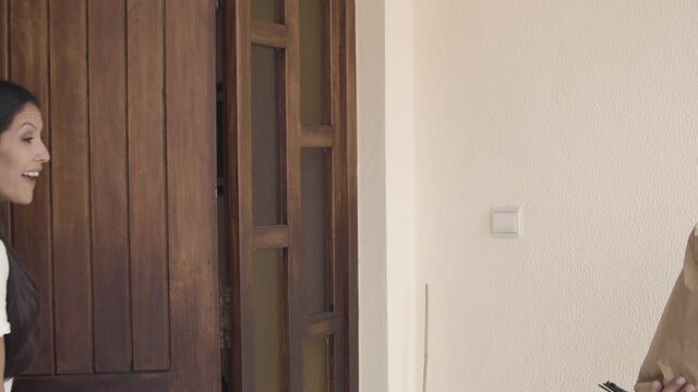 Deliveryman knocking at door and giving package with food to customer. Woman confirming receiving on tablet. Shipping or delivery service concept
