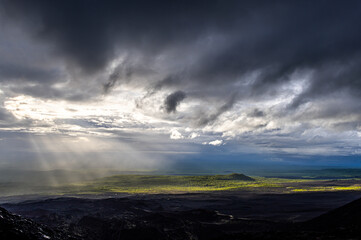 Sunset dark sky clouds twilight landscape and sun rays break through the clouds, illuminating the valley with light. 