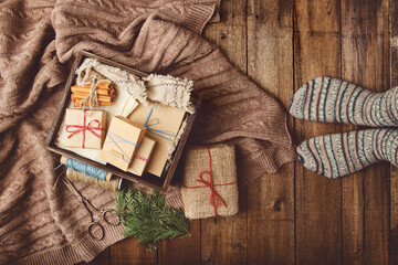Christmas, New Year composition with gift boxes, knitted blanket and women feet on wooden floor....