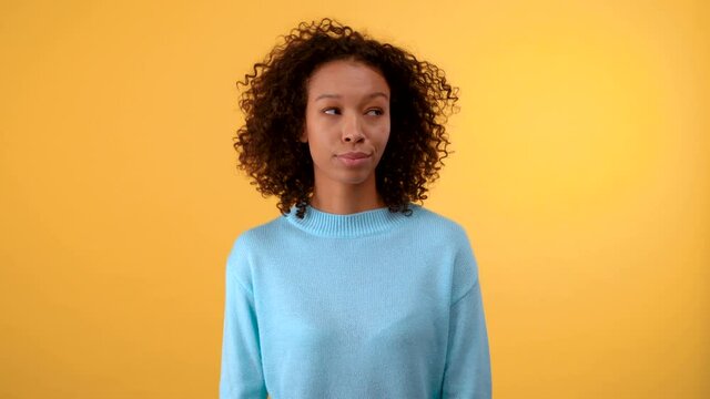 puzzled young woman on a yellow background touches her chin. The woman chooses between two options. Isolated on a bright yellow background. 4K