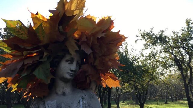 Sculpture of a girl with a wreath of leaves on a sunny day of golden autumn